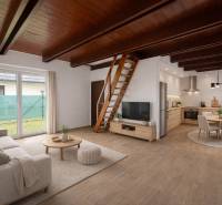 Obývací pokoj s kuchyní v rodinném domě, schody, sedačka, televizor, jídelní stůl, podlaha s dřevěným dekorem.