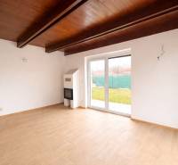 Interiér rodinného domu s podlahou s dřevěným dekorem a s velkými okny do zahrady.