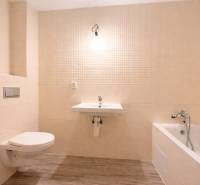 Koupelna v rodinném domě s vanou, umyvadlem a podlahou s dřevěným dekorem.