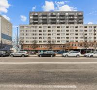 Budova na ulici Budatinská v Bratislavě - Petržalce s auty zaparkovanými před ní.