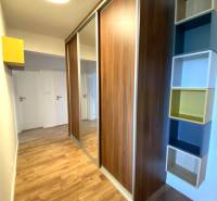 Ve 3-pokojovém bytě je vidět vestavěná skříň, podlaha s dřevěným dekorem a police.