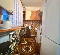 Kuchyně v 2-pokojovém bytě s dekorativním kobercem, stoličkami a dlaždicovou stěnou.