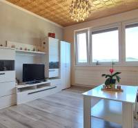 Pokoj v 2-pokojovém bytě s nábytkem, podlahou s dřevěným dekorem a dekoracemi.