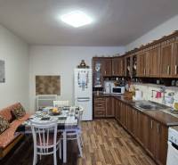 Kuchyně v rodinném domě s dřevěnými skříňkami a podlahou s dřevěným dekorem.