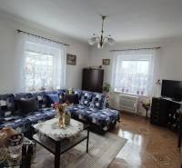 Rodinný dům s pohovkou, skříní, televizorem, dekoracemi a podlahou s dřevěným dekorem.