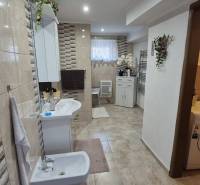 Koupelna v rodinném domě s kachličkovou stěnou, bidetem, pračkou a dekoracemi.