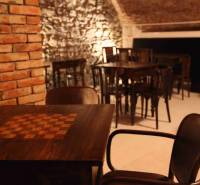 Rustikální gastro prostory s kamennými stěnami a podlahou s dřevěným dekorem.