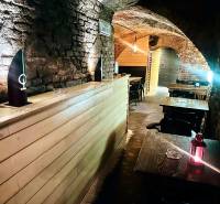 Kamenné stěny a oblouky v gastro prostorech s podlahou s dřevěným dekorem.