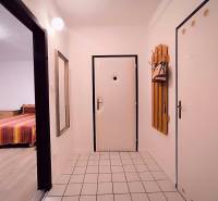 Chodba v 2-pokojovém bytě s bílými stěnami, dlažbou a zrcadlem.