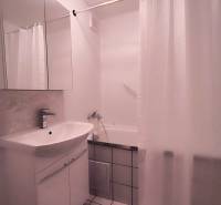 Koupelna v 2-pokojovém bytě s umyvadlem, zrcadlem, vanou a bílými dlaždicemi.