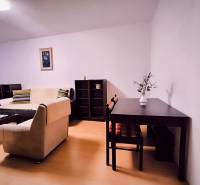 Obývací pokoj v 2-pokojovém bytě s podlahou s dřevěným dekorem, světlá pohovka, stolek.