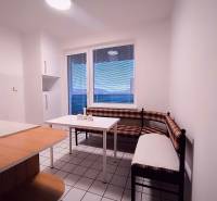 Kuchyně s rohovou lavicí, stolem a oknem v 2pokojovém bytě.