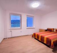 Ložnice s barevnou postelí a podlahou s dřevěným dekorem v 2pokojovém bytě.