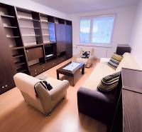 Obývací pokoj ve 2-pokojovém bytě s pohovkou, křesly a nábytkovou sestavou.