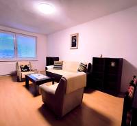 Obývací pokoj v 2-pokojovém bytě s minimalistickým nábytkem a podlahou s dřevěným dekorem.