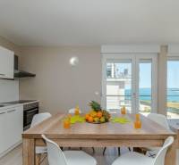 Rekreační apartmán s výhledem na moře, jídelní stůl a kuchyňská linka.
