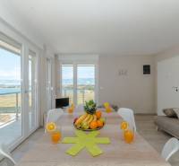 Jídelní stůl v rekreačním apartmánu s výhledem na moře přes velká okna.