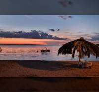 Fotografie zobrazuje večer na pláži s palmami a oceánem s oceněním realitní kanceláře Reality BICIAŇ.