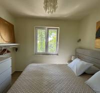 Ložnice v rodinném domě s uměním na stěnách a závěsným světlem.