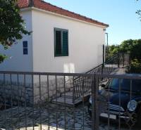 Rodinný dům v Čiovu se zahradou, schodištěm a zaparkovaným autem u vchodu.