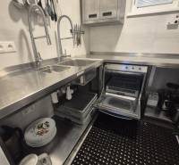 Kuchyně v gastro prostorech s nerezovými dřezy, spotřebiči a organizovanými kuchyňskými nástroji.