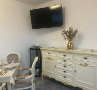 Elegantně zařízený interiér gastro prostor s televizorem na stěně a zdobeným nábytkem.