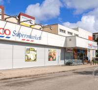 Supermarket Tesco na ulici Tatranská, v blízkosti paneláků a parkoviště.