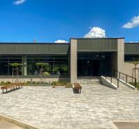 Na ulici Tatranská je vidět budova se zahradou, lavičkami a přístupovou cestou.