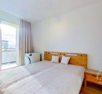 Ložnice v 3-pokojovém bytě s postelí a výhledem přes balkónové dveře.