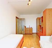 Pokoj v 3-pokojovém bytě s podlahou s dřevěným dekorem a jednoduchým nábytkem.