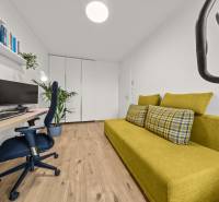 Pokoj ve 4pokojovém bytě se zelenou pohovkou, počítačem a podlahou s dřevěným dekorem.