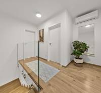 Chodba ve 4-pokojovém bytě s podlahou s dřevěným dekorem, zrcadlem a květinou.