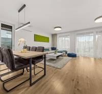 Jídelní a obývací prostor ve 4pokojovém bytě s podlahou s dřevěným dekorem.