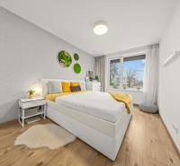 Ložnice s postelí a dekoracemi na stěně, podlaha s dřevěným dekorem.