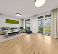 Obývací pokoj s pohovkou, prosklenými dveřmi a podlahou s dřevěným dekorem ve 4pokojovém bytě.