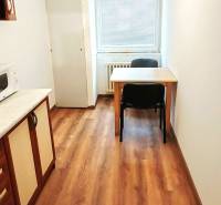 Kuchyně v 3-pokojovém bytě s podlahou s dřevěným dekorem a stolem pro dvě osoby.