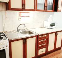 Kuchyně v 3-pokojovém bytě s podlahou s dřevěným dekorem a kuchyňskou linkou.