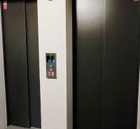 Dva výtahy s kovovými dveřmi a ovládacím panelem mezi nimi.