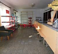 Interiér obchodních prostor s pultem, regály a křeslem.