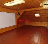 Podkrovní prostor s dřevěným dekorem v obchodních prostorách, s malým střešním oknem.