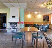 Obchodní prostory se stylovými židlemi, stolem a krbem, vhodné pro akce.