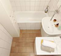 Koupelna v 2-pokojovém bytě s vanou, umyvadlem a pračkou.