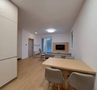 Obývací pokoj v 2pokojovém bytě s podlahou s dřevěným dekorem a otevřenou kuchyní.