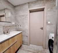 Koupelna s umyvadlem a podlahou s dřevěným dekorem v 2-pokojovém bytě.