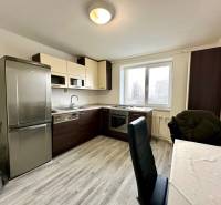 Kuchyně v 2pokojovém bytě s podlahou s dřevěným dekorem a stolem se židlemi.