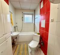 Koupelna ve 2-pokojovém bytě s vanou, umyvadlem a bílými dlaždicemi.