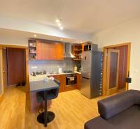 Kuchyně v 2-pokojovém bytě s podlahou s dřevěným dekorem a barovým pultem.