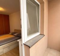 Ložnice v 2pokojovém bytě s postelí, podlahou s dřevěným dekorem a přístupem na terasu.