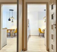 Osvětlená jídelna s kuchyňským stolem a žlutými židlemi v 1-pokojovém bytě.