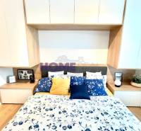 Ložnice v 3pokojovém bytě s podlahou s dřevěným dekorem a květinovým povlečením.